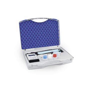 Ein offener Koffer mit Schaumstoff, enthält Messgeräte, Fläschchen und Reagenzien, auf einer grauen Fläche.