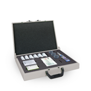 Ein geöffneter Koffer enthält mehrere Flaschen, Probenbehälter und Umschläge, alle in einem Schaumstoff-Inlay, auf einer grauen Fläche liegend.