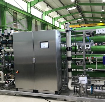 Eine industrielle Anlage mit Edelstahlgehäuse und Rohren steht in einer großen Halle.