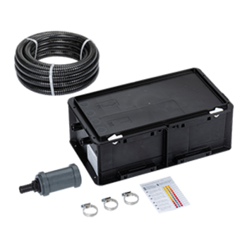 Eine rechteckige schwarze Kunststoffbox mit Kabelanschlüssen liegt auf Tisch, daneben eine aufgerollte Kabelspule, drei Metallverbindungen und ein kleiner Zettel mit farbigen Streifen.